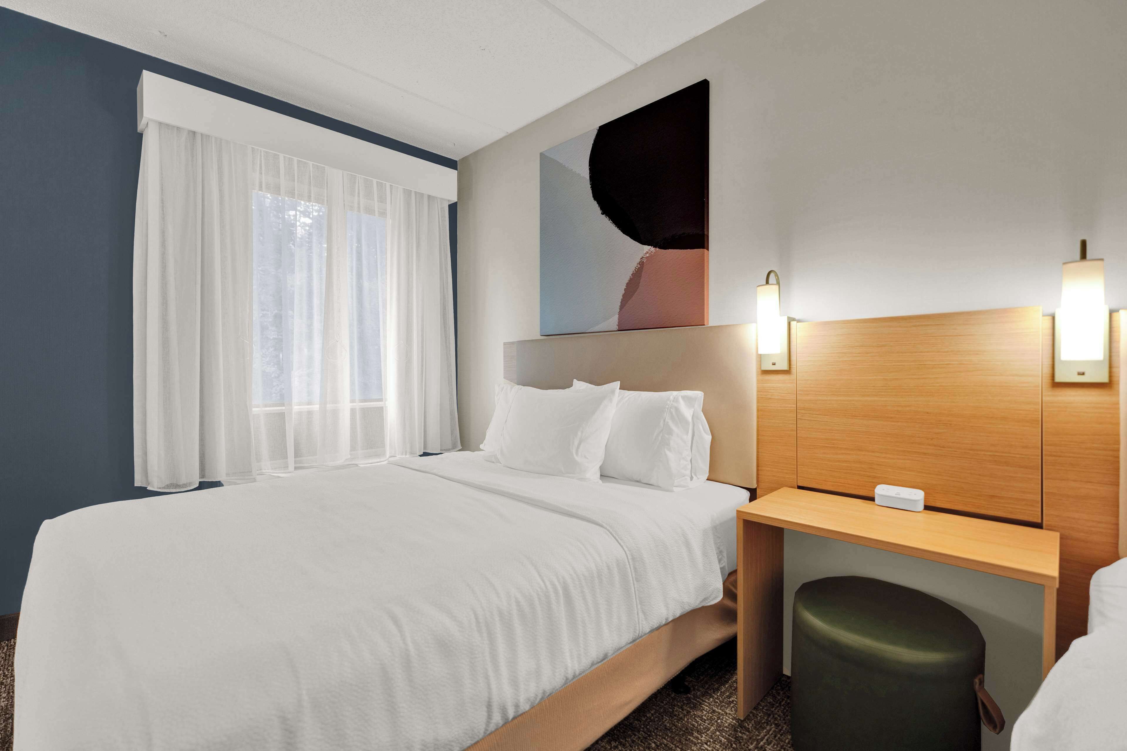 Una habitación de hotel con una cama, un escritorio y una silla.