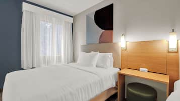 Una habitación de hotel con una cama, un escritorio y una silla.