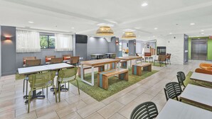 A modern indoor dining area with multiple tables and chairs, a green carpet, and pendant lighting. - Spark by Hilton Plymouth (Plymouth)