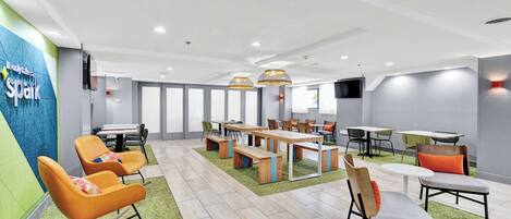 A modern conference room with a green carpet, wooden tables, and orange chairs.
