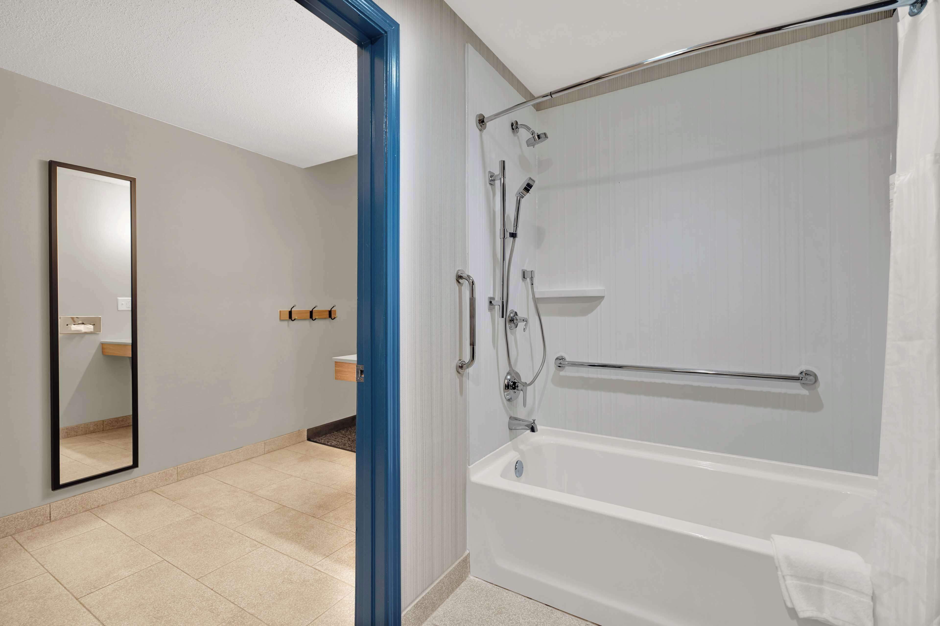 Un baño moderno con ducha de vidrio, bañera blanca y un espejo grande.
