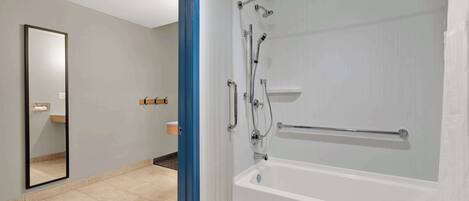 Un baño moderno con ducha de vidrio, bañera blanca y un espejo grande.
