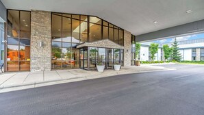 A modern building with large glass windows, a stone facade, and a small covered entrance. - Spark by Hilton Plymouth (Plymouth)