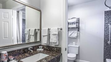Un baño con lavamanos de encimera de granito, un espejo grande y un perchero con varias toallas.