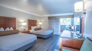 A hotel room with two beds, a desk, a chair, and a TV. - Aloha Inn (Arroyo Grande)