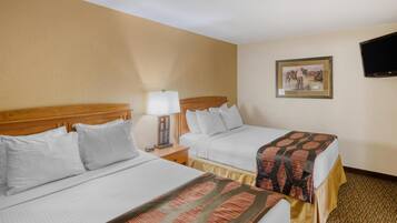 Two single beds with white linens, a wooden headboard, a bedside table with a lamp, and a framed picture on the wall.
