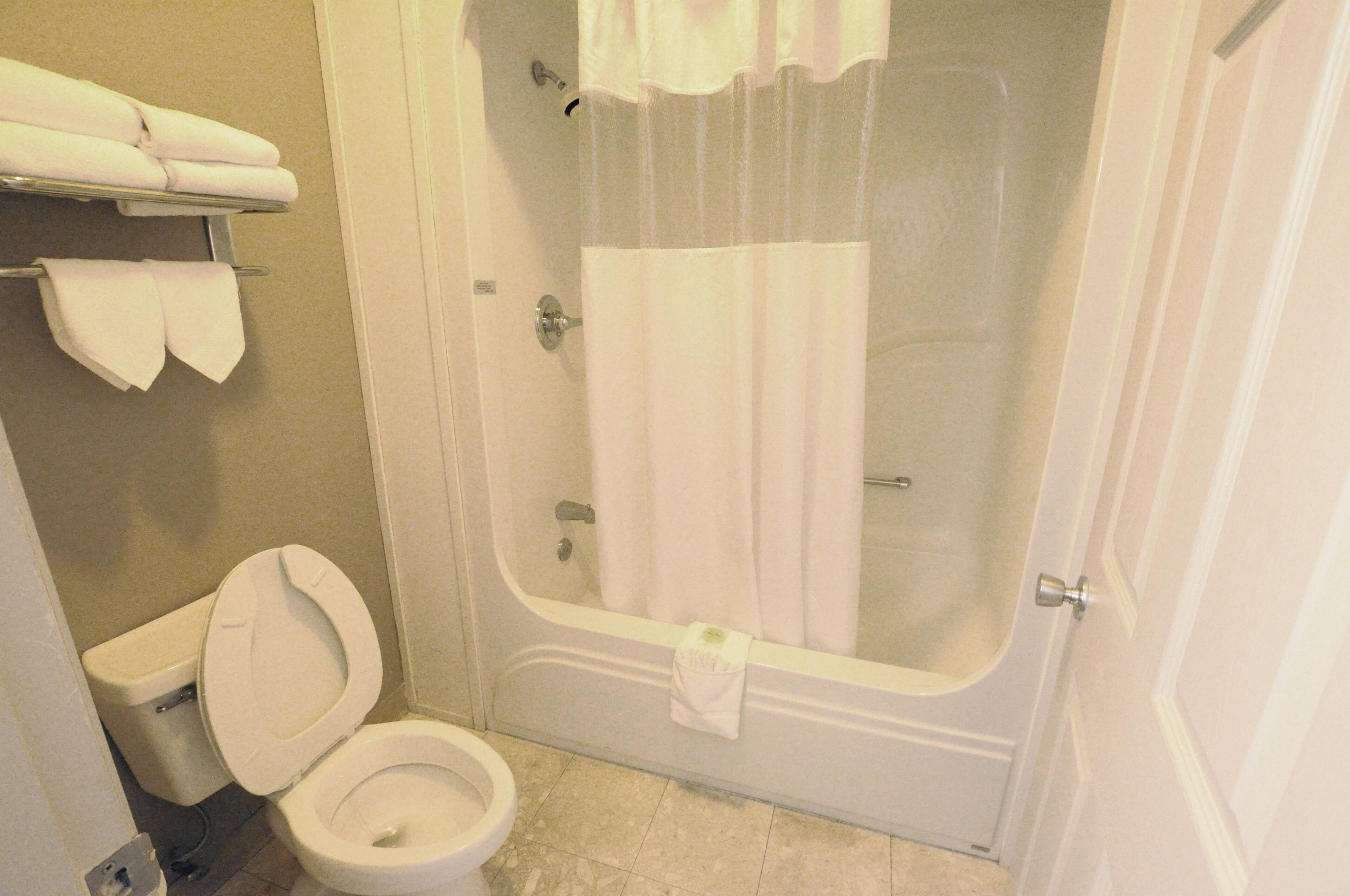 Un baño con inodoro, bañera y cortina de ducha.