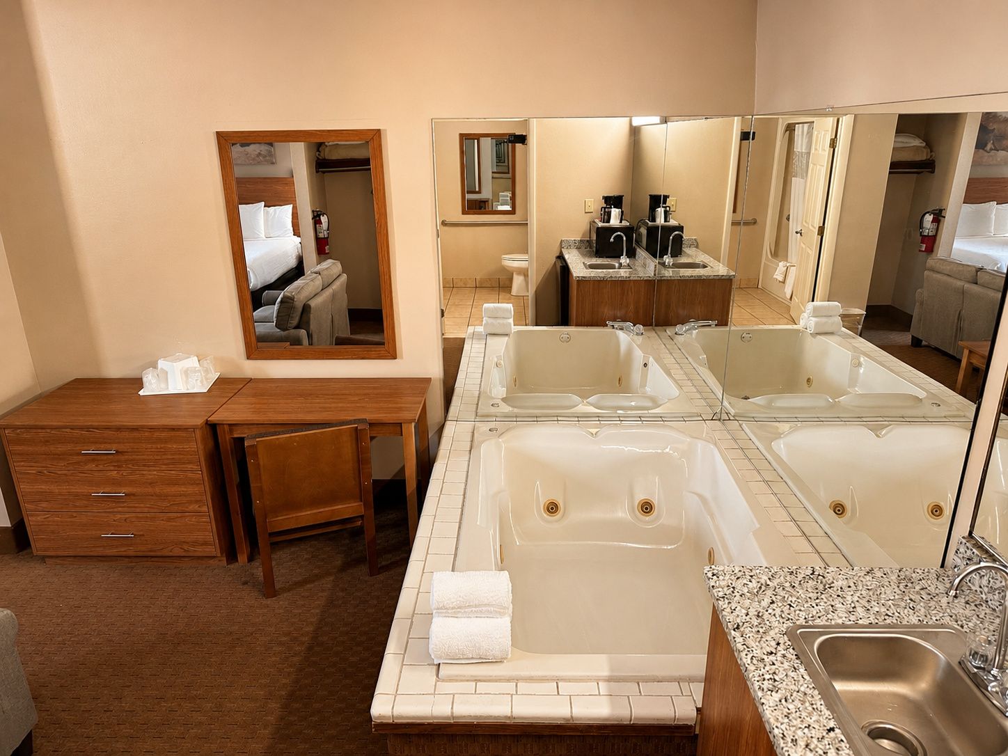 A hotel bathroom with a large bathtub, a sink, and a mirror.