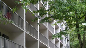 Un immeuble à plusieurs étages doté de balcons donnant sur un ruisseau aux rives rocheuses.
