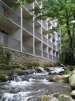 A multi-story building with balconies overlooking a rocky stream.