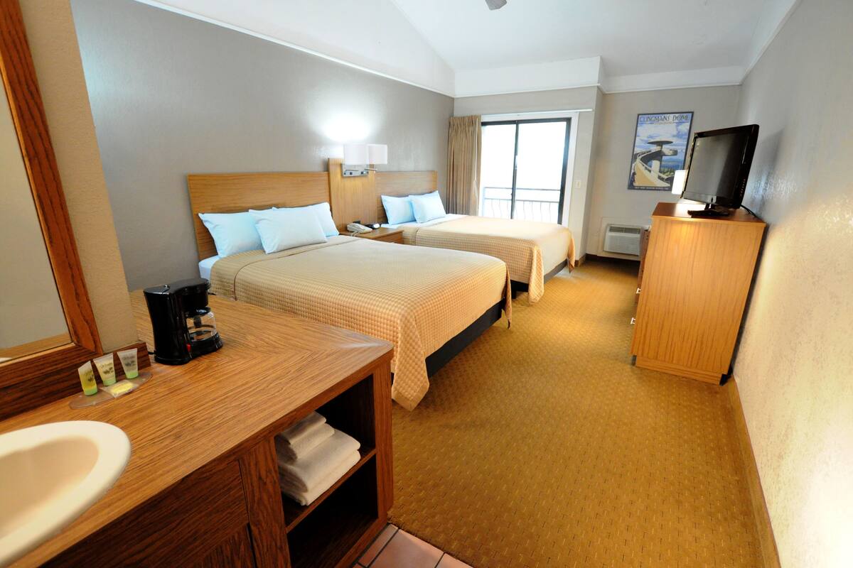Une chambre d’hôtel avec deux lits, une salle de bain, une télévision et une fenêtre.