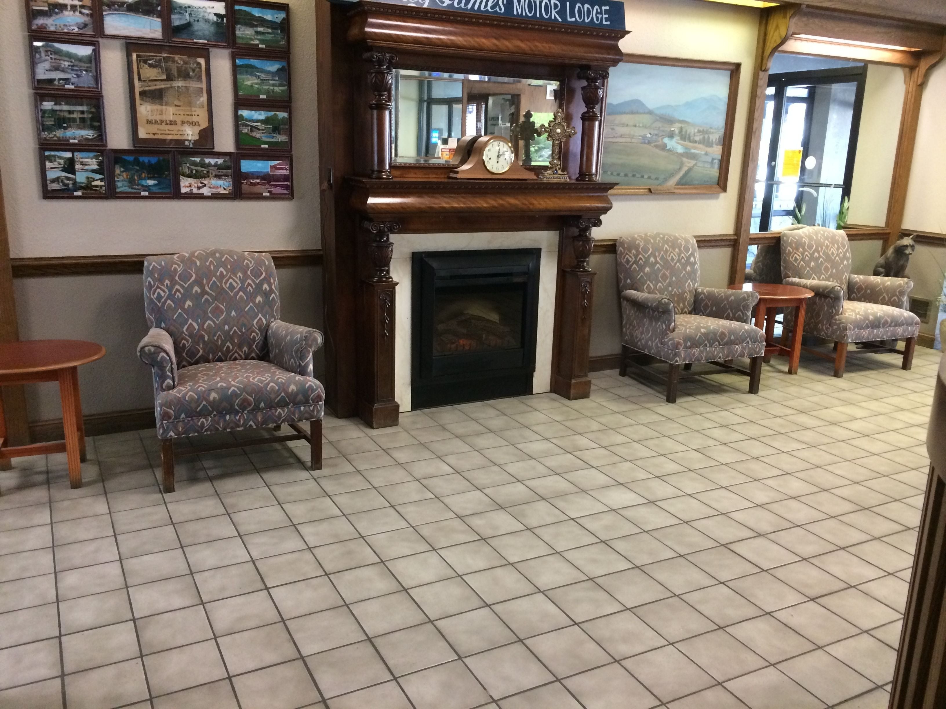 Un hall acogedor con sillones estampados, una chimenea y una pared decorada con fotografías.