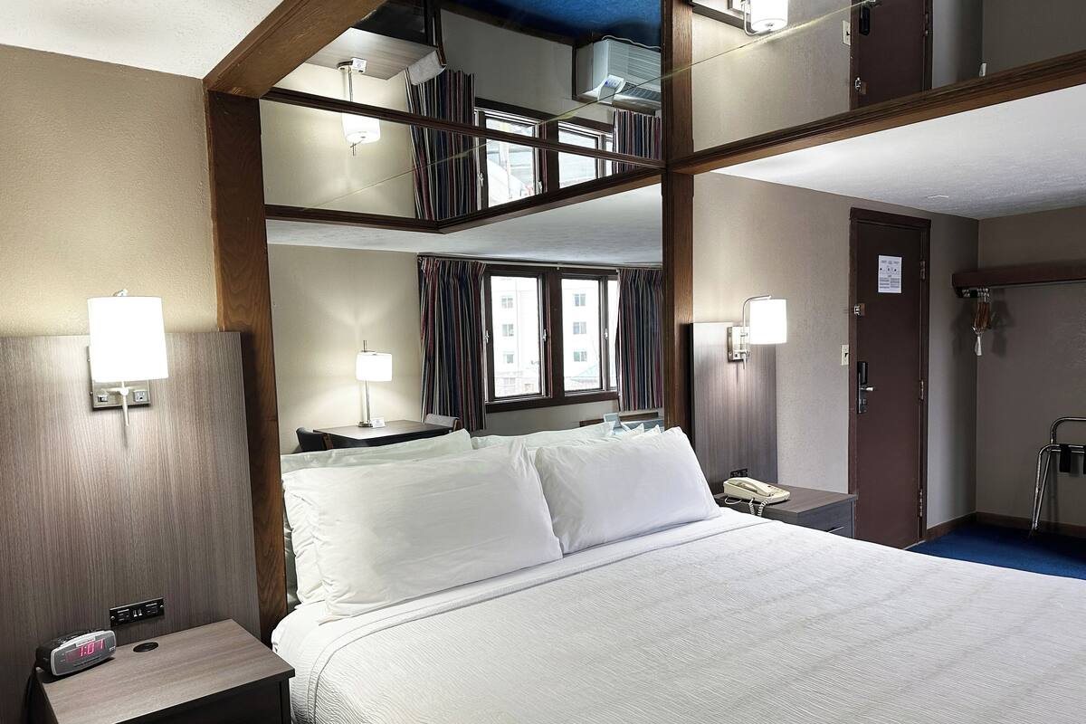Une chambre d’hôtel équipée d’un lit, d’une table de chevet, d’une lampe et d’un téléphone.