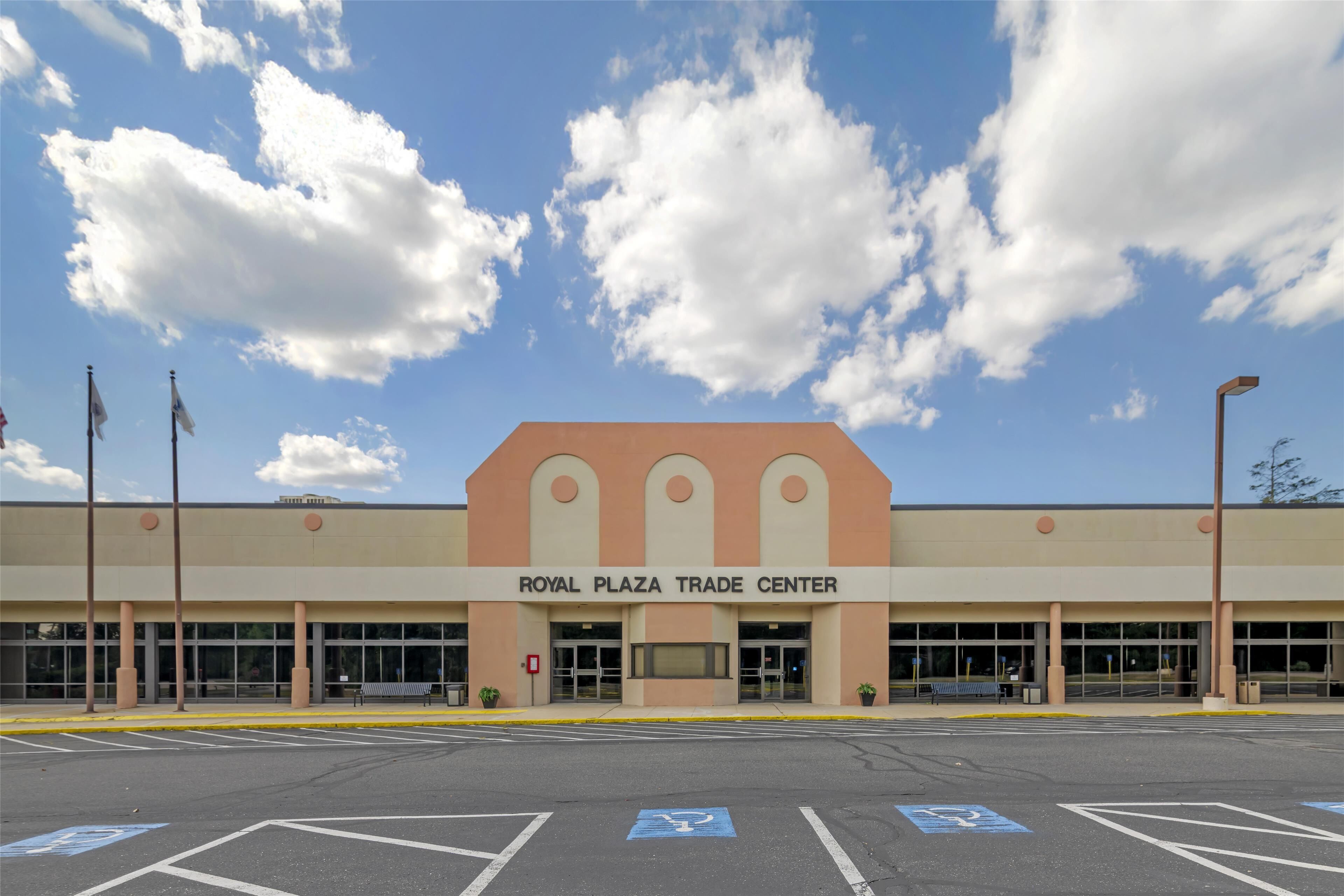 A building with a sign reading "Royal Plaza Trade Center" under a partly cloudy sky.