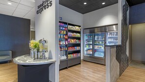 A modern interior with a self-service kiosk, refrigerated display cases, and a seating area.