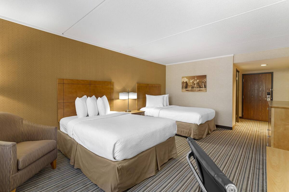 Een hotelkamer met twee bedden, een slaapbank, een bureau en een lamp.