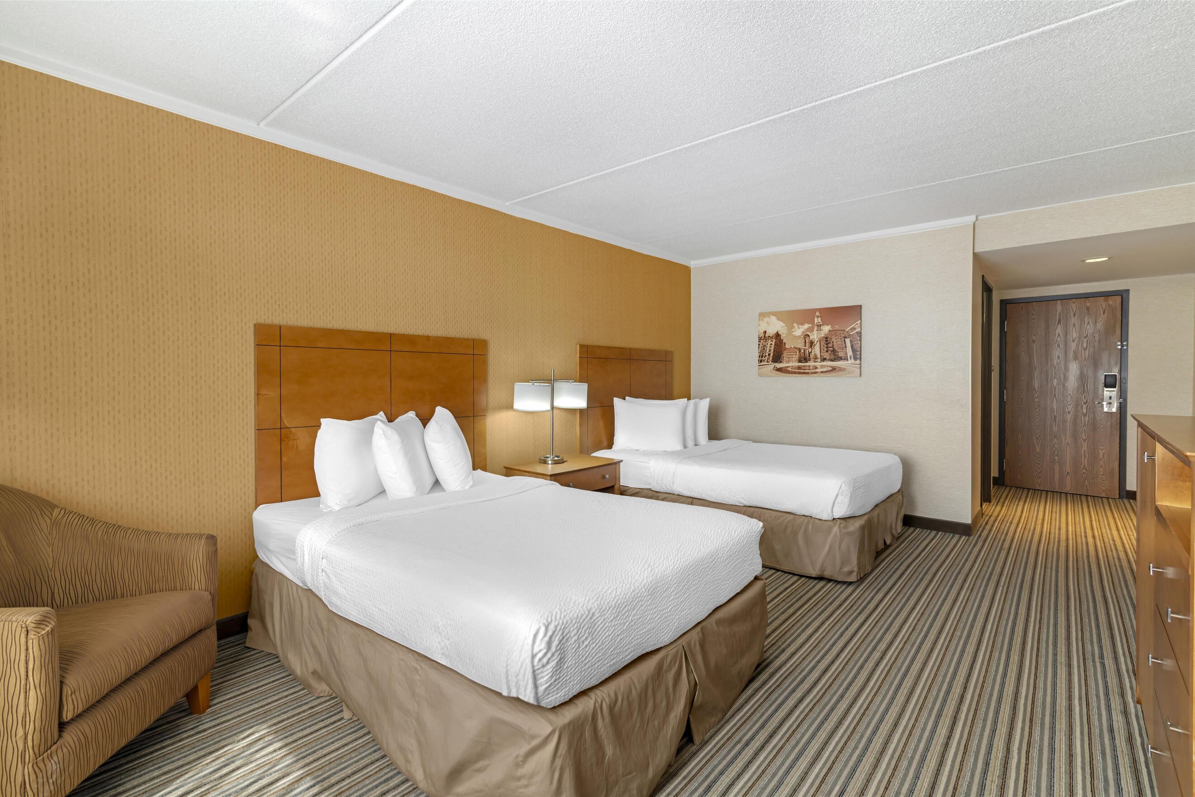Habitación de hotel con dos camas, un sofá, un escritorio y una lámpara.