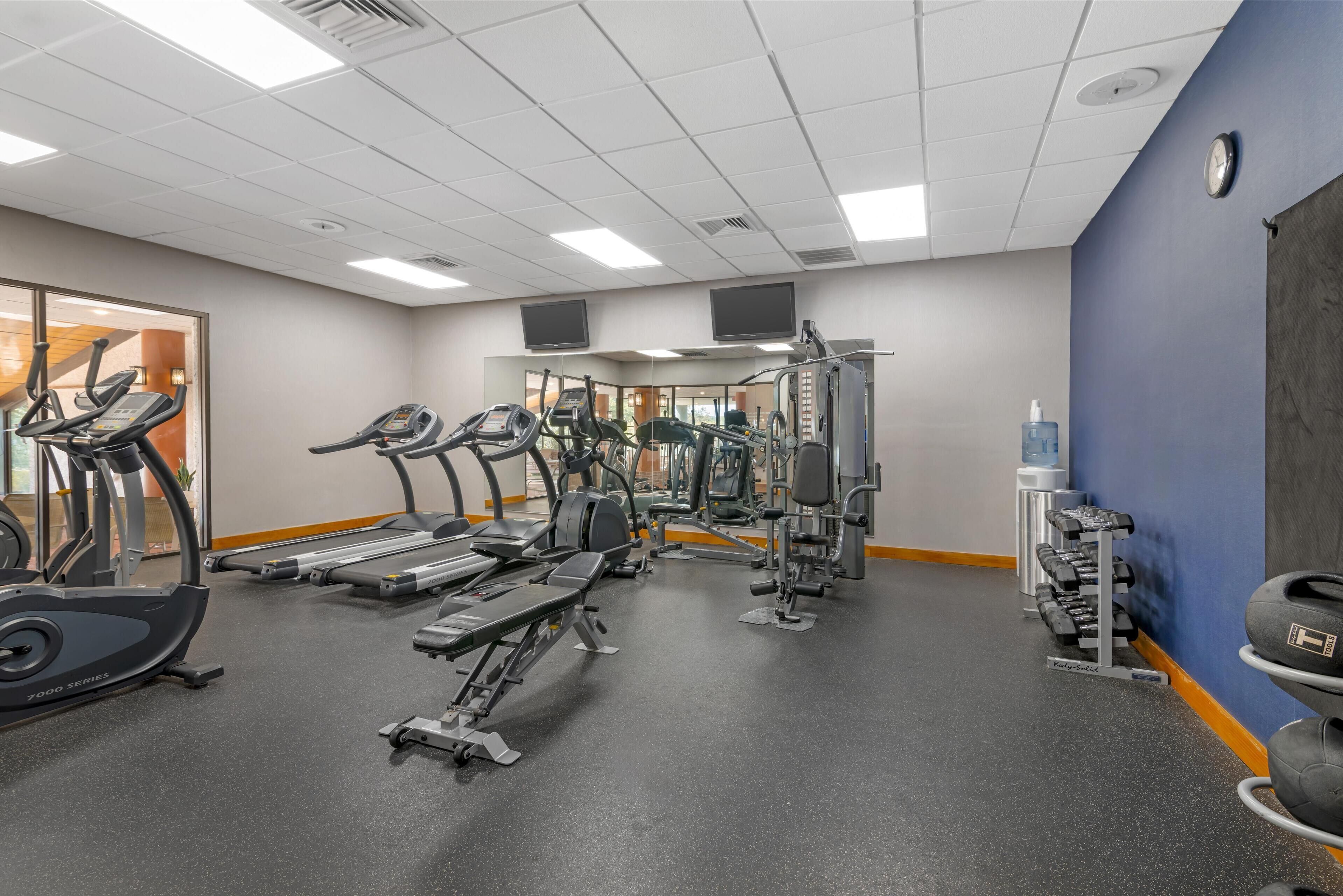 A gym with treadmills, elliptical machines, and weightlifting equipment.