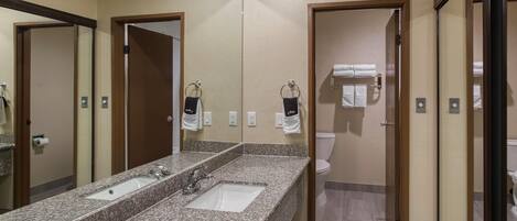 Ein Badezimmer mit Granitwaschtisch, einem Spiegel und einer Toilette, die durch eine offene Tür sichtbar ist.