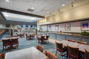 A hotel lobby with a seating area, a counter with a menu, and a view of the kitchen in the background. - SureStay Plus Hotel by Best Western Price (Price)