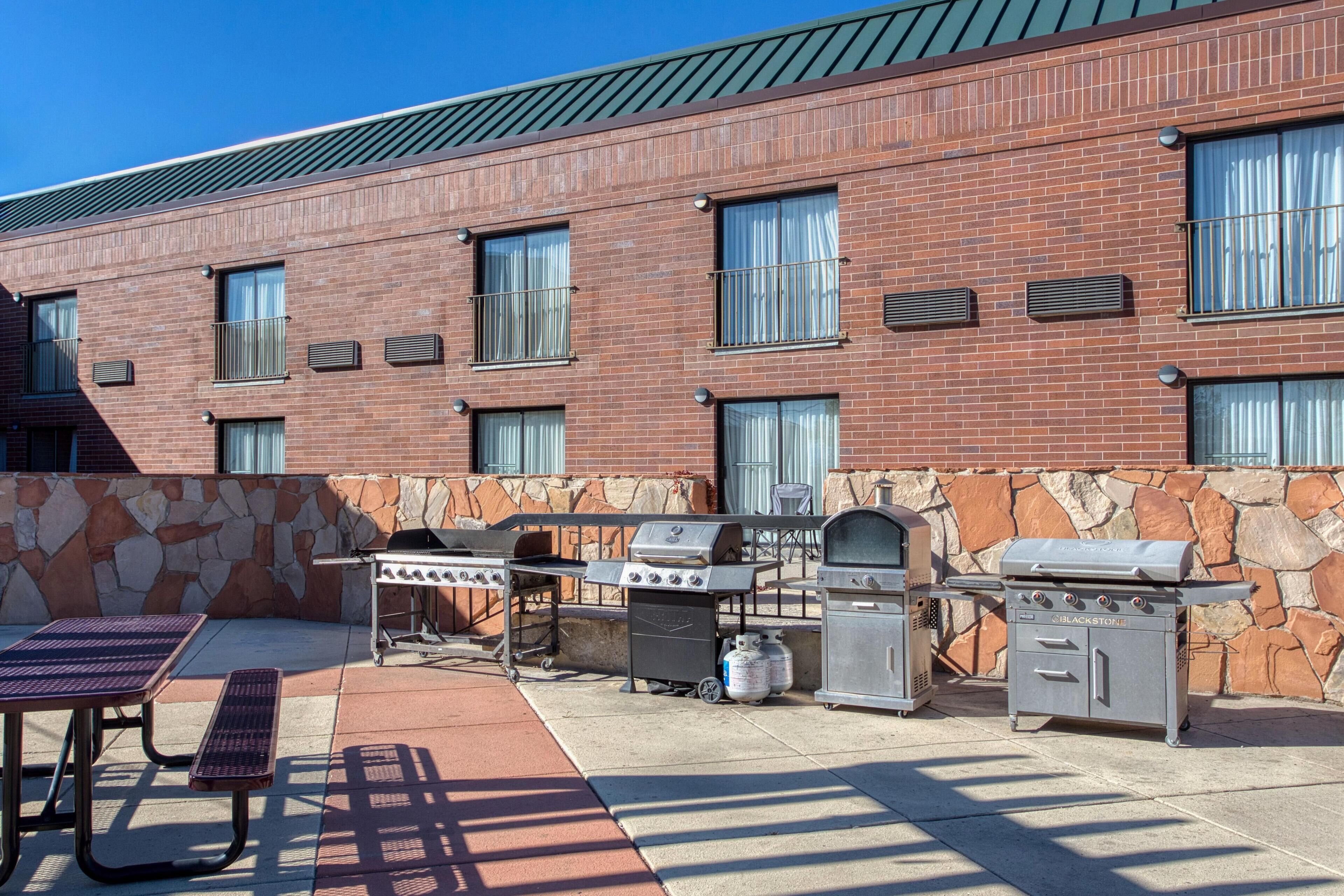 An outdoor patio with a brick building, stone wall, and a grill station.