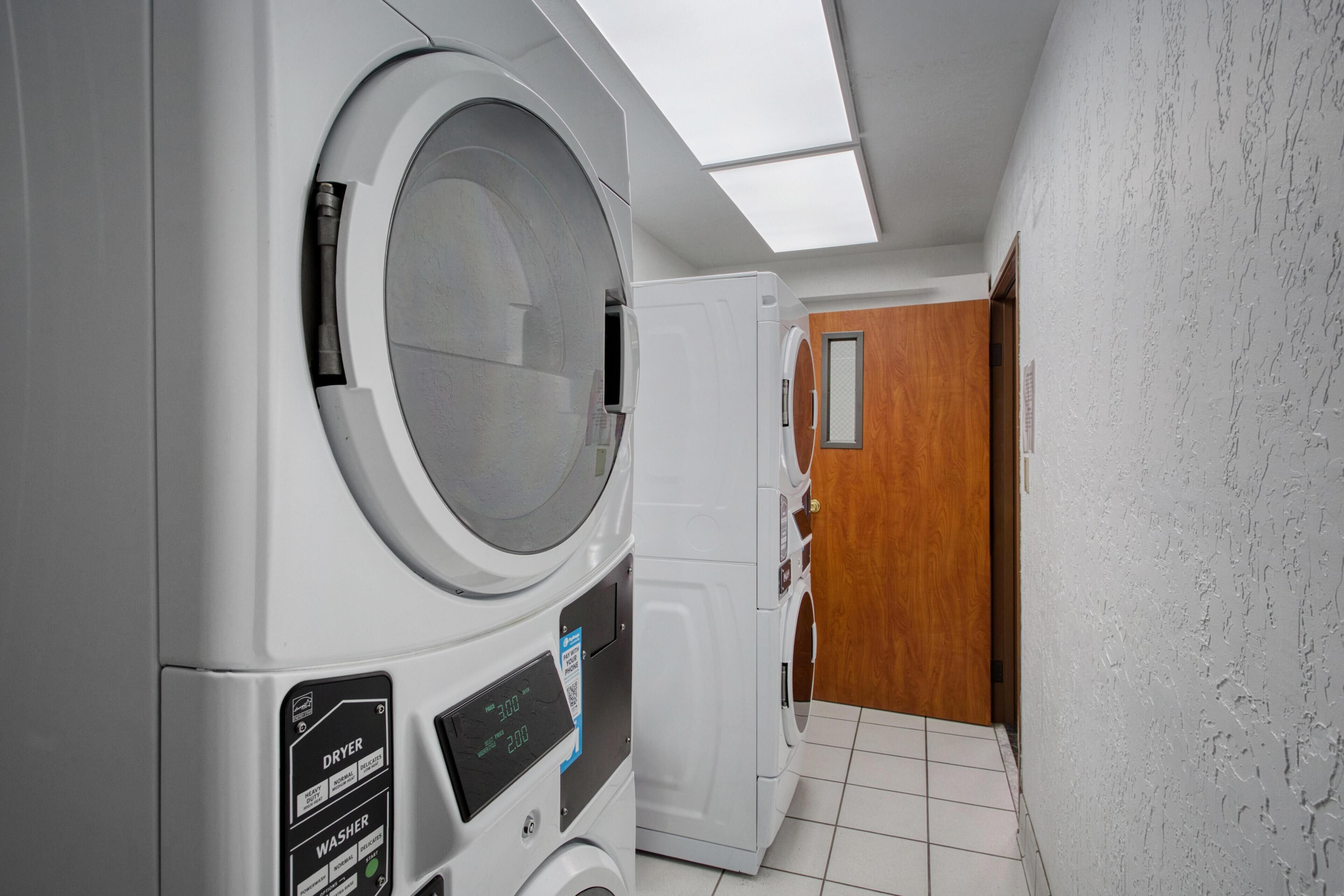 A laundry room with a dryer, washer, and a wooden door.