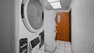 A laundry room with a dryer, washer, and a wooden door.