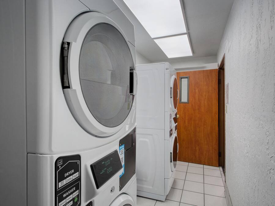 A laundry room with a dryer, washer, and a wooden door.