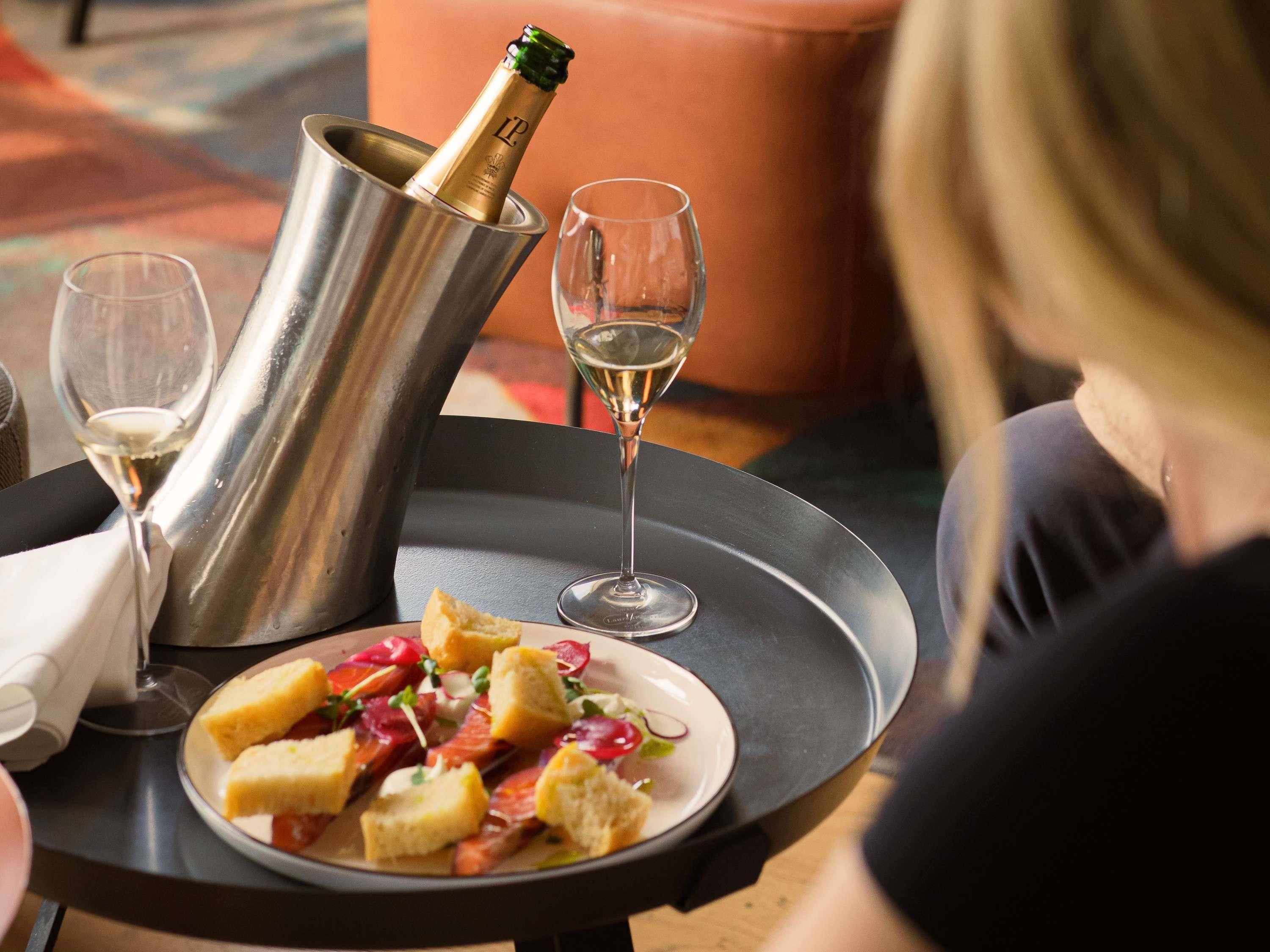 A table with a plate of food, a bottle of champagne, and two glasses.