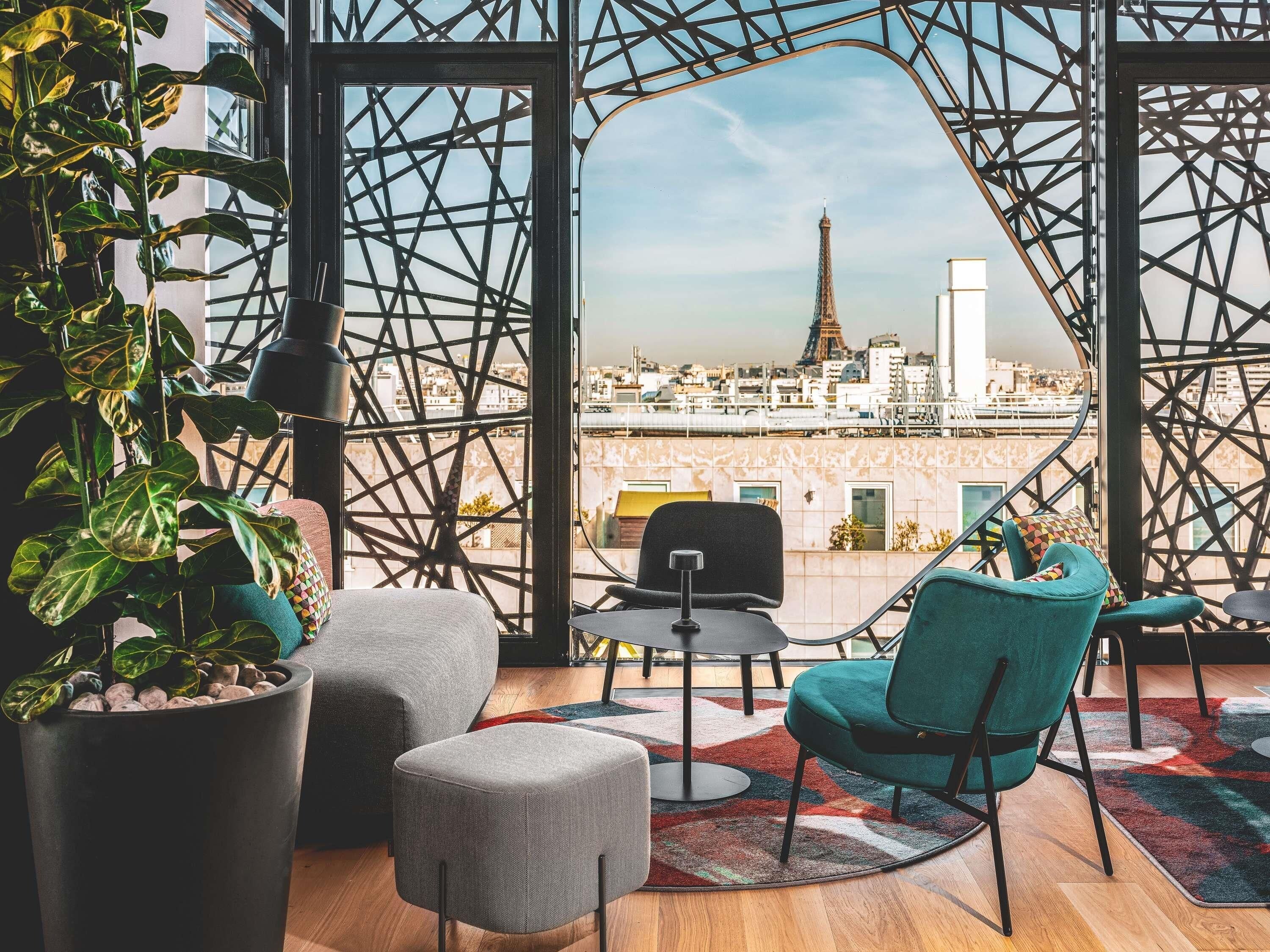 A modern interior with a view of the Eiffel Tower, featuring a geometric metal structure, a potted plant, and contemporary furniture.
