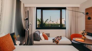 Een hotelkamer met een bed, een zithoek, een bureau en uitzicht op een stadsgezicht.