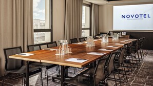 Un salón de conferencias con una larga mesa, sillas y una pantalla proyectora que muestra