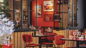 A restaurant interior with red chairs, a patterned floor, and a bar area with bottles and glasses.