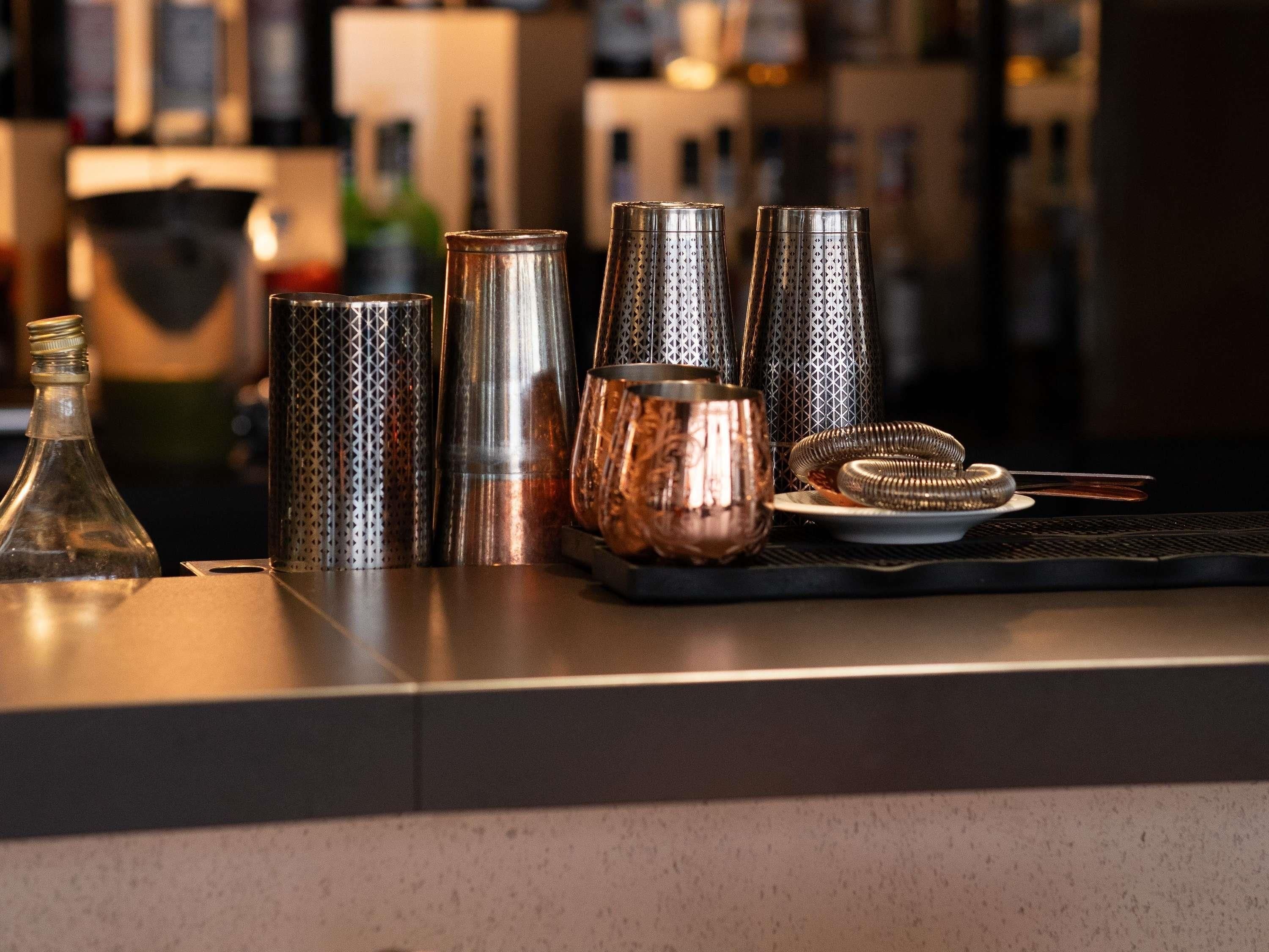 Un comptoir de bar avec différents shakers en métal et une tasse en cuivre.