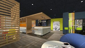 A modern reception area with a reception desk, a seating area with a blue couch, and a wall with patterned shelves. - ibis budget Besancon Centre Gare (Besancon)
