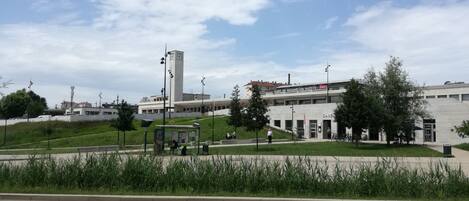 Un edificio con una torre del reloj, un cartel que dice "GARE DE BESANCON VIOTTE" y una zona ajardinada con bancos.