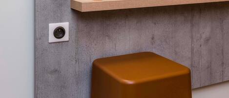 A modern interior with a concrete wall, a wooden shelf with glasses, and a brown stool.