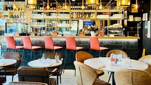 A restaurant interior with a bar area, multiple seating options, and a variety of bottles and glasses on shelves. - ibis budget Besancon Centre Gare (Besancon)