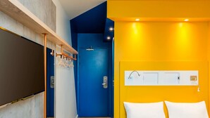 A hotel room with a bed, a door, a wall-mounted light, and a wall-mounted TV. - ibis budget Besancon Centre Gare (Besancon)