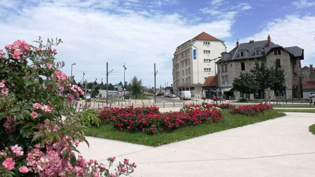 A hotel with a modern design, a central courtyard with flowers, and a clear blue sky. - ibis budget Besancon Centre Gare (Besancon)