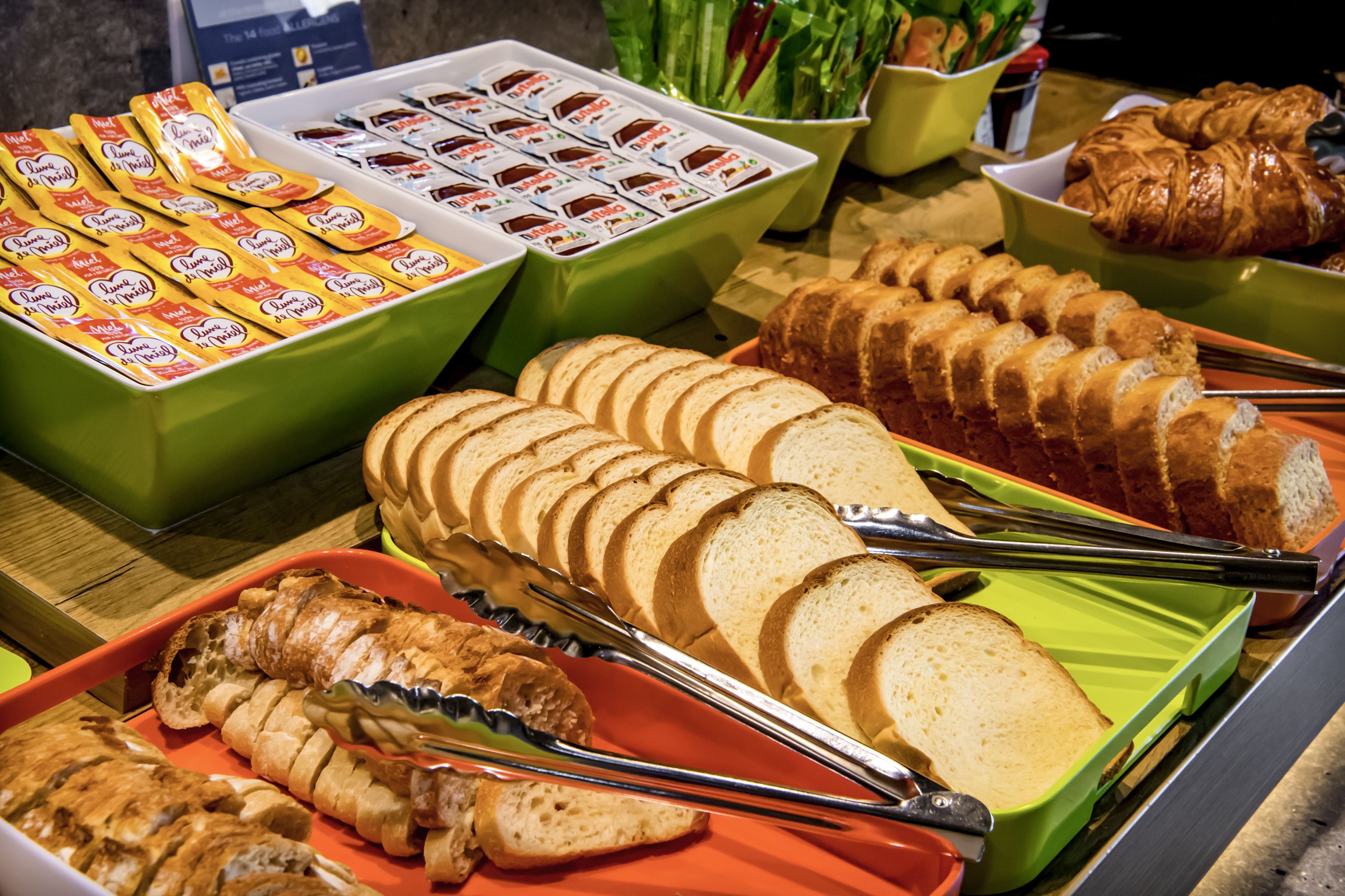 A buffet with various food items including bread, pastries, and packaged snacks.