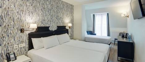 A hotel room with a large bed, bedside tables, a desk, a chair, and a TV.