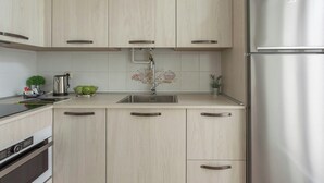 A modern kitchen with light wood cabinets, stainless steel appliances, and a central island with a sink. - Sercotel Hotel Europa (San Sebastián)
