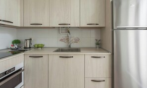 Eine moderne Küche mit hellen Holzschränken, Edelstahlgeräten und einer zentralen Kochinsel mit Spüle.