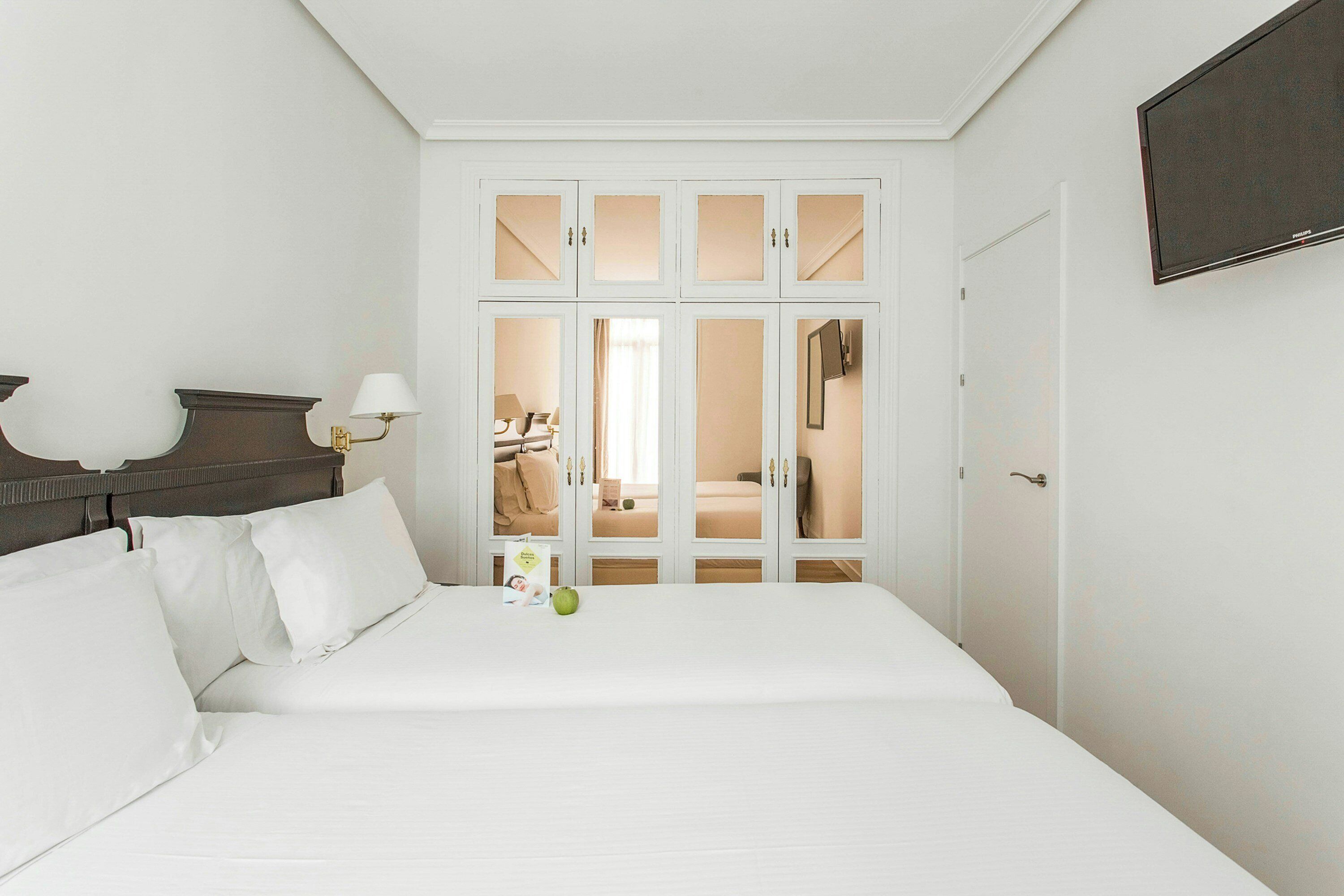 A hotel room with a large bed, a nightstand, a lamp, and a wardrobe with mirrored doors.