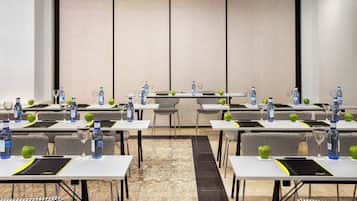 Un salón de conferencias con varias mesas, sillas y botellas de agua.