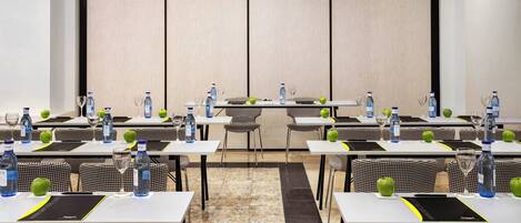 A conference room with multiple tables, chairs, and water bottles.