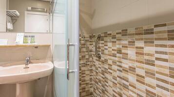 Un baño con cabina de ducha de vidrio, lavamanos y zona de ducha con azulejos.