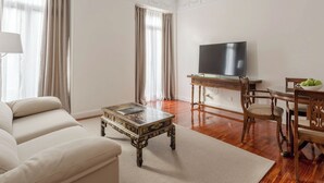 A living room with a sofa, a coffee table, a TV, a dining table with chairs, and a window with curtains. - Sercotel Hotel Europa (San Sebastián)