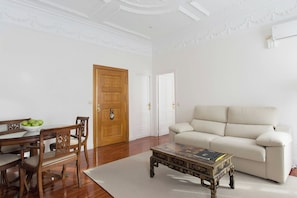 A living room with a wooden dining table, chairs, a beige sofa, and a decorative coffee table. - Sercotel Hotel Europa (San Sebastián)